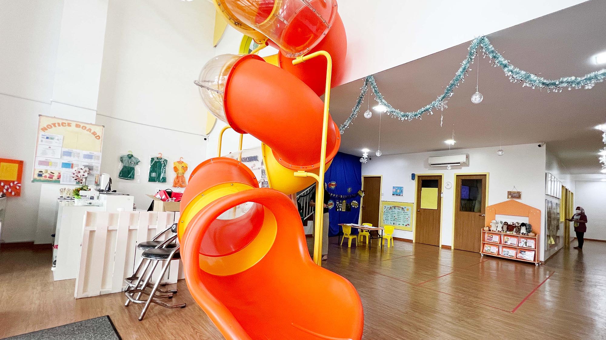 Eduwis Cyberjaya kindergarten interior with a bright red spiral slide and engaging activity spaces, providing a fun learning environment for young children.
