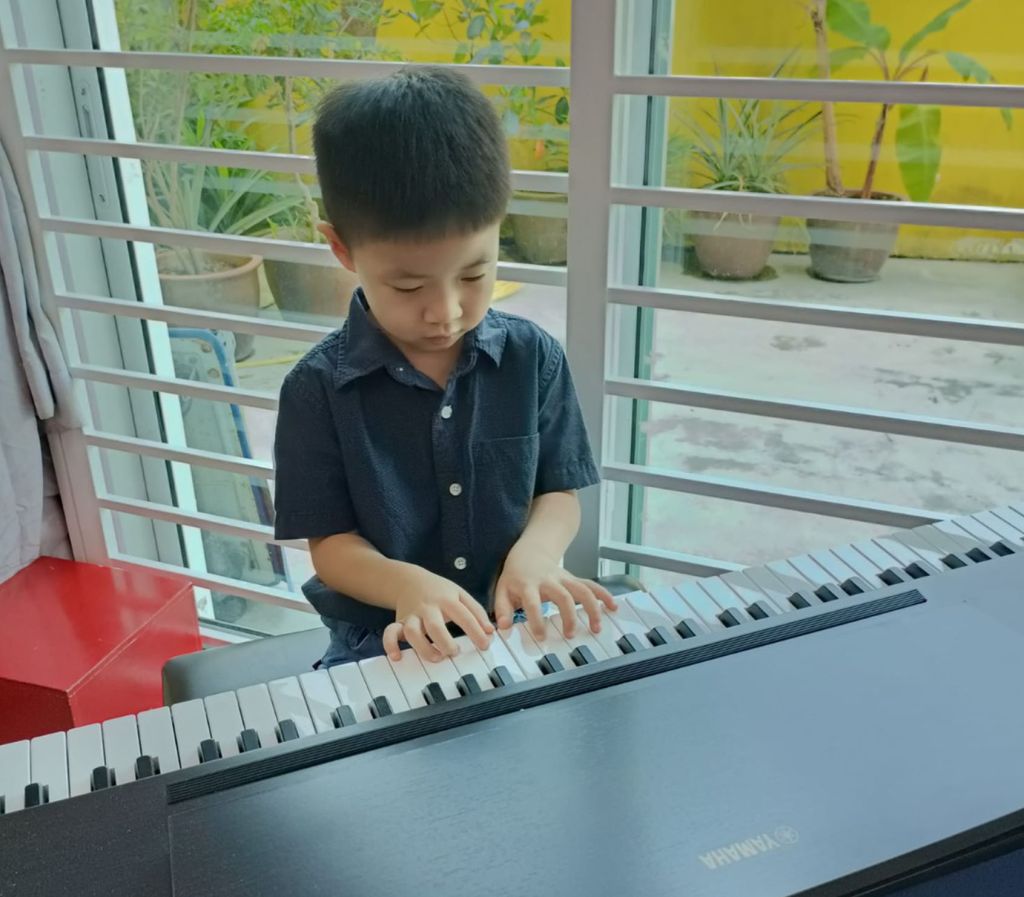 A young preschool girl in Ipoh is being taught how to play the piano & A little boy playing the piano.