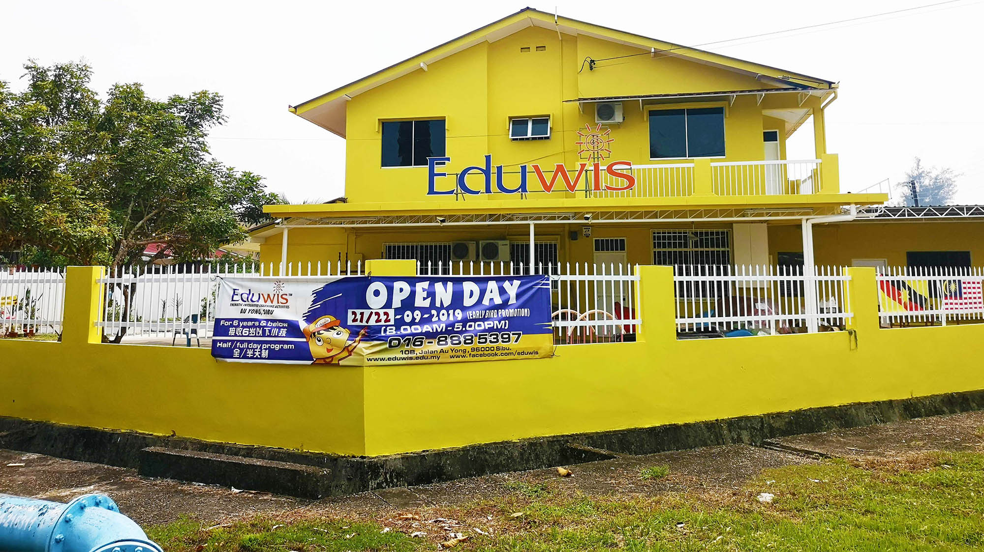 Exterior of Eduwis kindergarten in Sibu, featuring a bright yellow building with a welcoming open day banner, providing early education in a friendly environment.